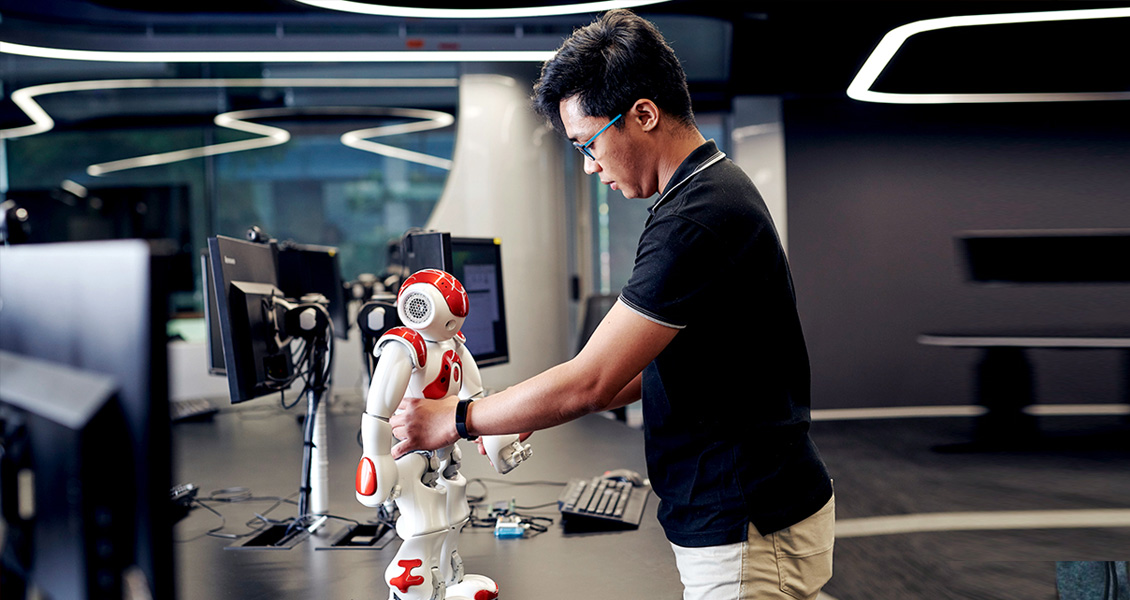 The image shows the man in a black shirt holding a robot.