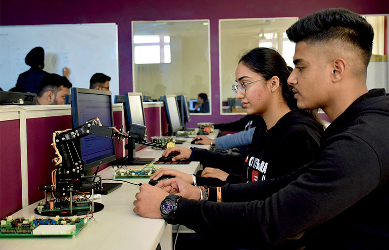The image shows the students of chitkara university in a black sweatshirt working on the desktop.