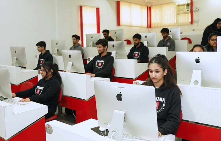 The image shows the students of chitkara university in black sweatshirts working on the desktops.