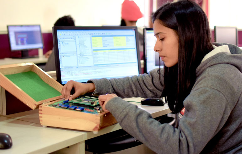 The image with a blurred background shows the girls sitting in front of the desktop and working on their cse project.