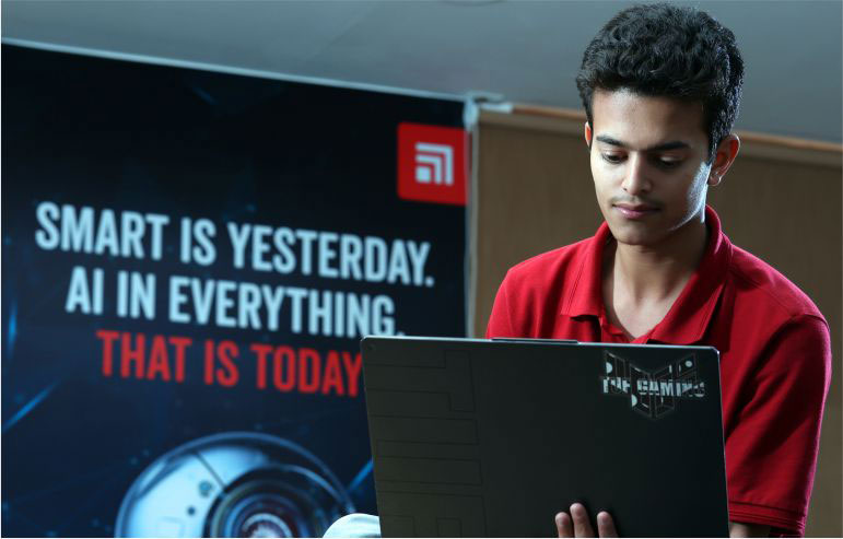 Image with dark blue background with logo of chitkara university.The center of image says "SMART IS YESTERDAY. AI IS EVERYTHING in text and THAT IS TODAY in red text. On right side of image a boy holding a laptop in red t-shirt.