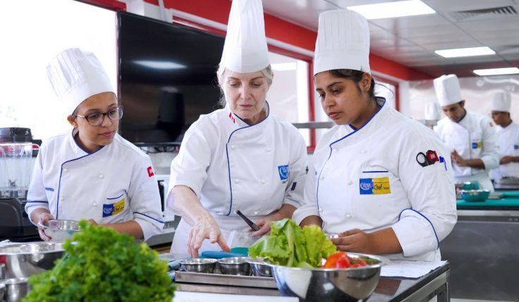 Students pursuing a Degree in Culinary Arts practicing cooking skills with an instructor at George Brown College kitchen.