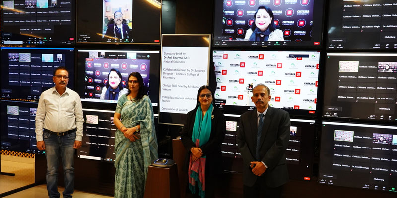 Panelists and dignitaries at Chitkara University’s E-Conference on COVID-19 Management standing in front of multiple digital screens.